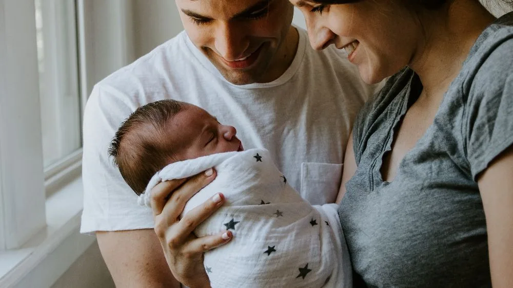 Man en vrouw kijken naar hun ingebakerde baby, vooraanzicht