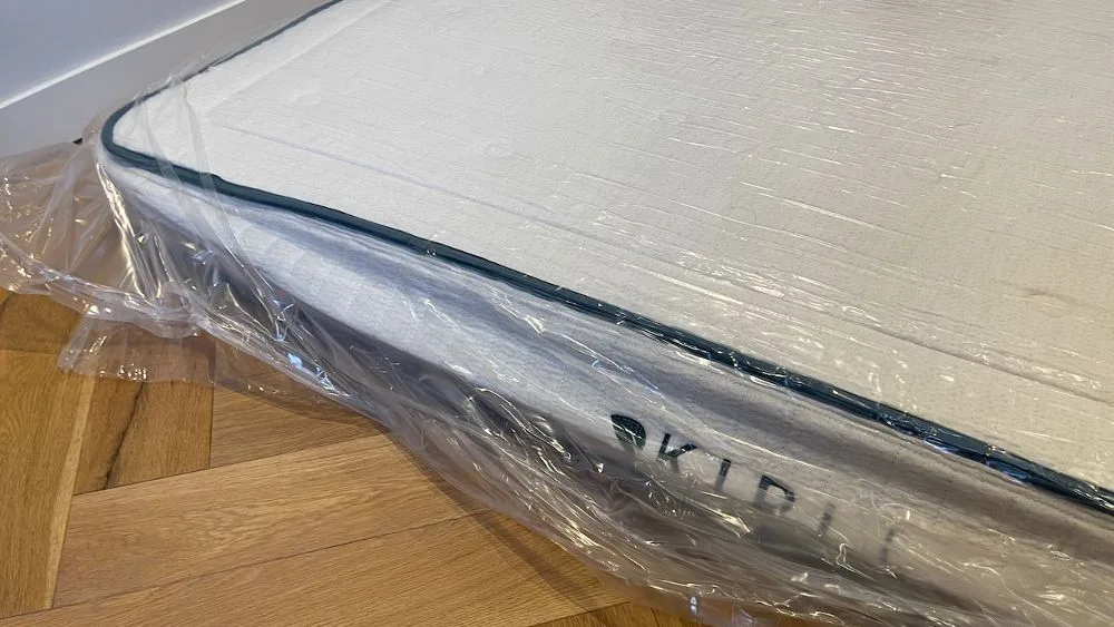 Matras verpakt in plastic op de grond, schuin bovenaanzicht