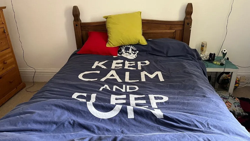 Bed met blauw dekbed en groen kussen