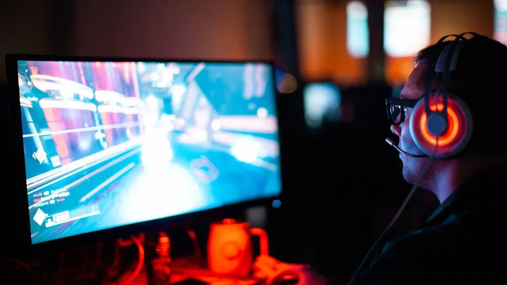Gamer met koptelefoon voor een scherm, zij-aanzicht