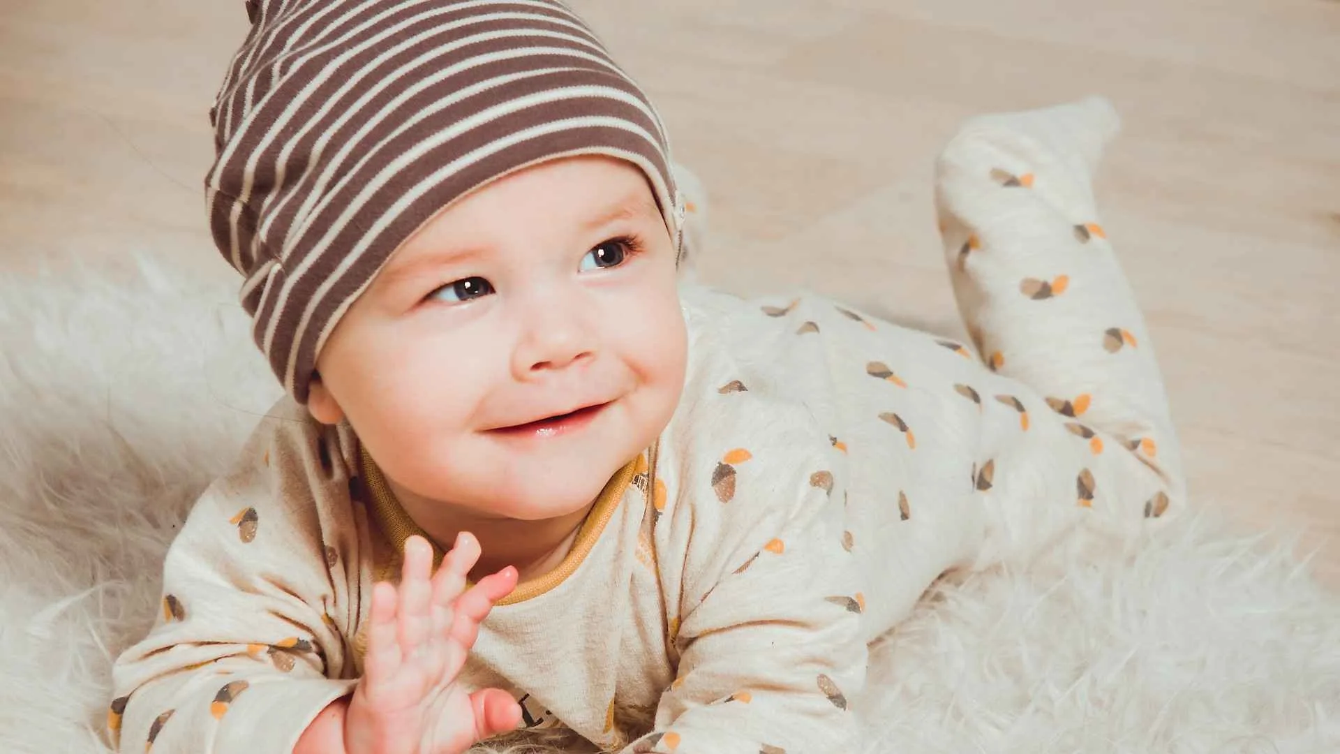 Lachende baby in cremekleurig pakje, vooraanzicht