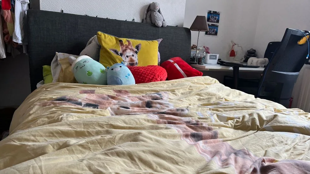 bed met geel dekbed en kussens op bed